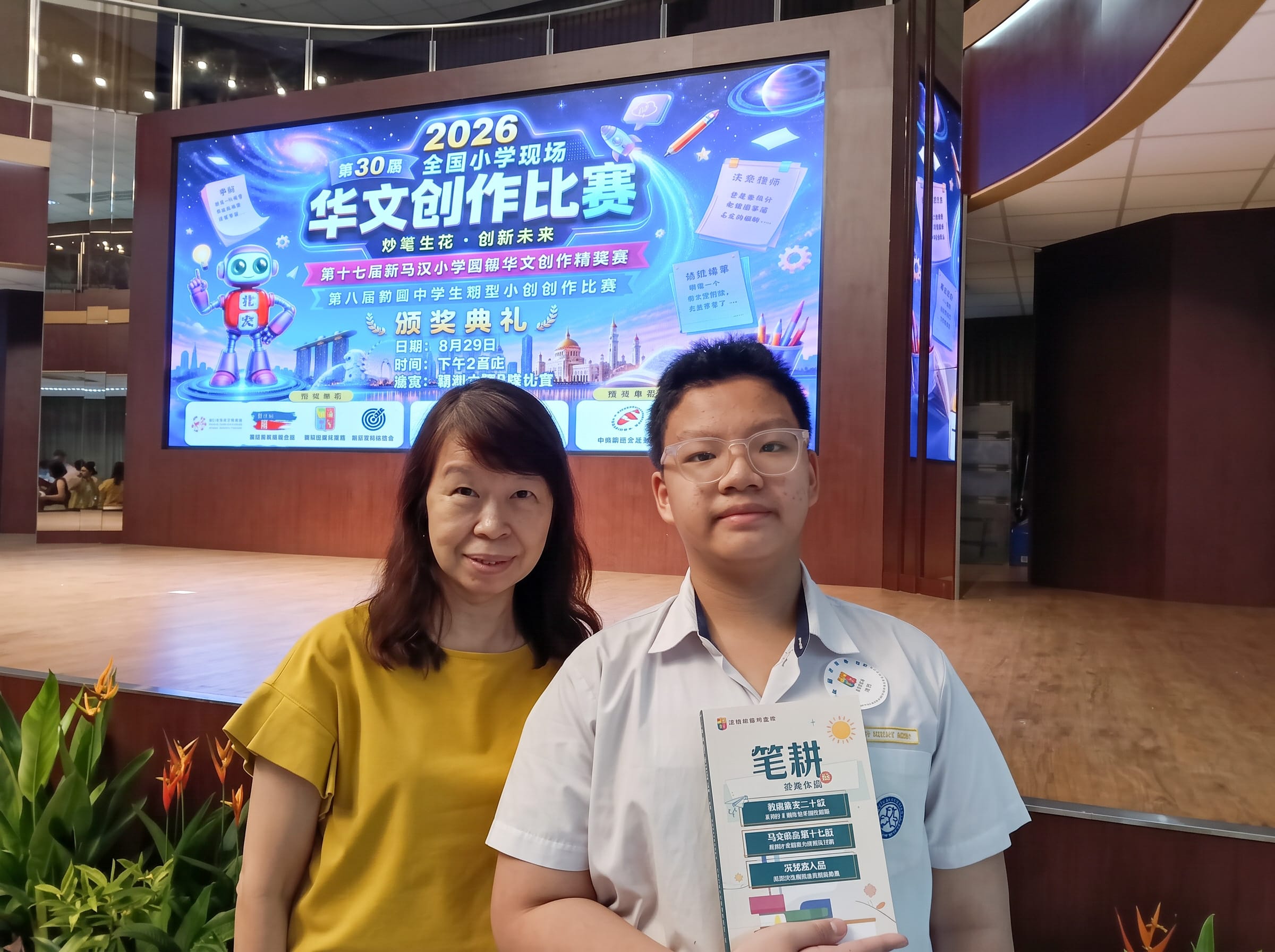 A woman and a teenage boy holding a certificate on stage (left), and the same boy holding a book with a woman in a yellow top (right), both in front of Chinese screens for the National Mandarin Creative Writing Competition.